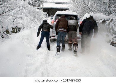 Group Of Men Pushing The Vehicvle Trapped In Snow, Outdoor Blurred Motion Shot