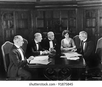 Group Of Men Sitting With A Young Woman In A Boardroom