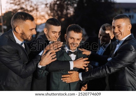 A group of men in suits are hugging each other. Scene is happy and friendly
