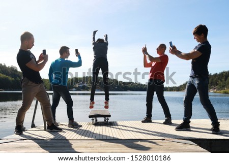 Group of men take it picture how woman in clothes jumping in cold  water in autumn season in Baltic sea, Sweden at beautiful view nature.