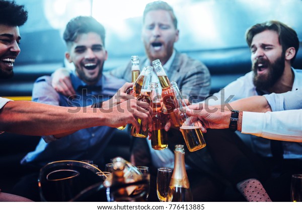 Group of men toasting with\
beer