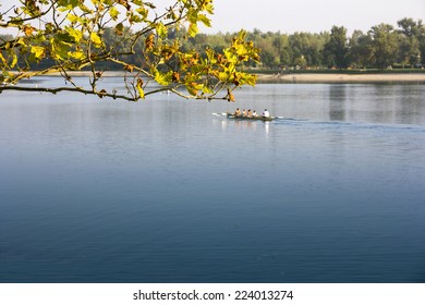 A group of men and women in the boat, rowing in the calm lake - Powered by Shutterstock