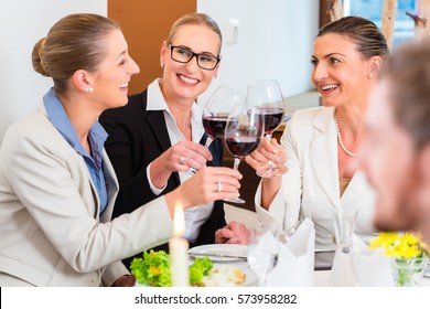 Group Of Men And Women At Business Lunch In Restaurant Eating And Drinking