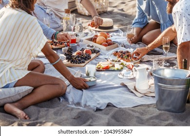 Group of men and women enjoying eating food on beach summer party.