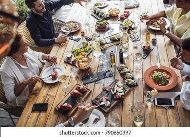 Group Of Men And Women Enjoying Outdoor Dinner Celebration.