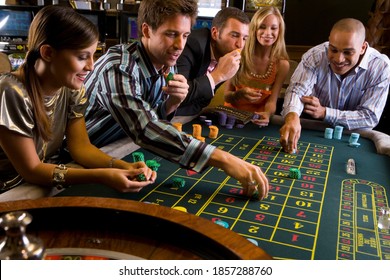 Group of men and women enjoying their time and gambling at the roulette table in a casino - Powered by Shutterstock