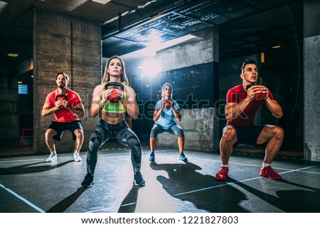 Group of men and women exercising with kettlebell.