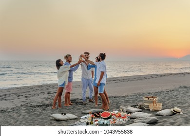 Group of men and women having fun toasting with champagne on beach party.