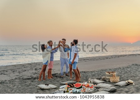 Group of men and women having fun toasting with champagne on beach party.