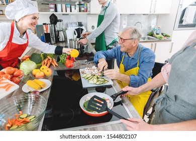 Group of men and women learning cooking in training kitchen with nutritionist - Powered by Shutterstock