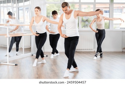 Group of men and women rehearsing ballet moves in dance studio - Powered by Shutterstock