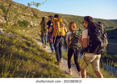 Group Of Men And Women Walk In A Row Along The Trail During A Walking Tour Of The Mountains. Adventure, Travel, Tourism, Hike And People Concept. Camping Season.