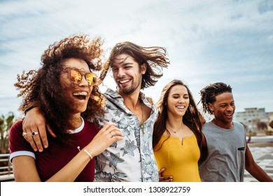 Group of men and women walking down the street talking and having fun. Multi-ethnic friends walking outdoors together. - Shutterstock ID 1308922759