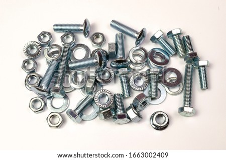 A group of metal products, bolts, nuts, washers is shot close-up. Details are stacked in a small pile.