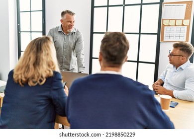 Group Of Middle Age Business Workers Listening Boss Speech During Meeting At The Office.