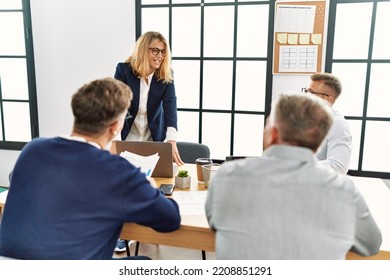 Group Of Middle Age Business Workers Listening Boss Speech During Meeting At The Office.