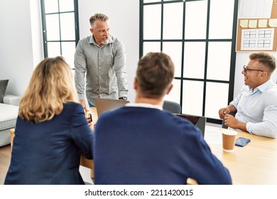 Group Of Middle Age Business Workers Listening Boss Speech During Meeting At The Office.