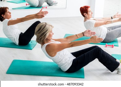 Group Of Middle Aged Women Doing Abdominal Exercise In Gym.