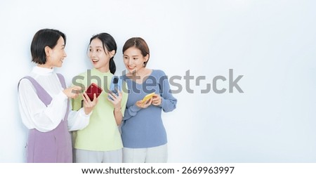 A group of middle-aged women talking while looking at their smartphones