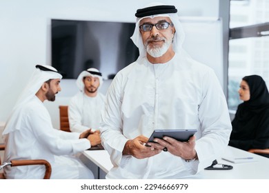 Group of middle-eastern corporate business people wearing traditional emirati clothes meeting in the office in Dubai - Business team working and brainstorming in the UAE