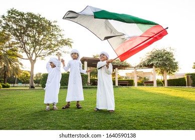 Group of middle-eastern kids wearing white kandora playing in a park in Dubai - Happy group of friends having fun outdoors in the UAE
