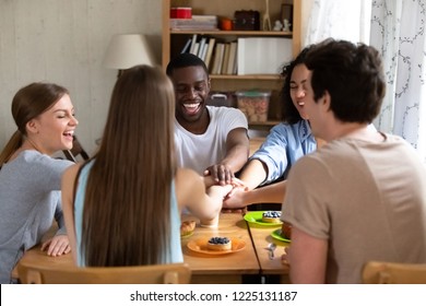 Group Of Millennial Diverse Students Stacked Putting Holding Hands Together Sitting Around The Table At University Or College Dormitory Room. Friendship Between Like-minded Mixed Race People Concept