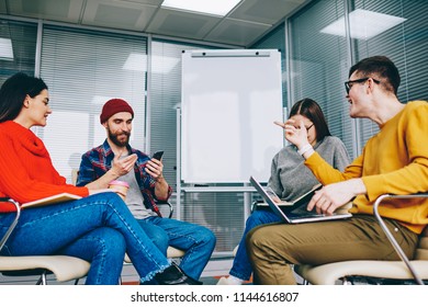 Group Of Millennial Hipster Students Dressed In Casual Wear Discussing Website And App Using Modern Technology And Wireless Internet During Courses In Classroom With Flip Chart With Mock Up Area