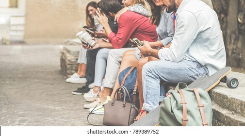 Group of millennials friends using smartphones  outdoor - Happy people having fun with technology trends after university lesson - Youth and friendship concept - Focus on right man mobile phone