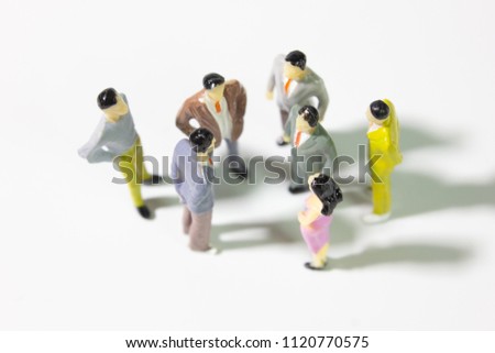 A group of miniature businessman 
stand meeting on white background top view closeup.