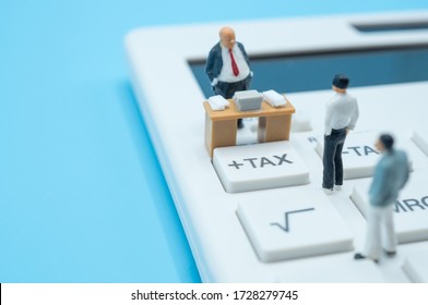 A group of miniature businessmen stand on calculator tax button, consider impact of covid-19 outbreak to economic, finance, income and tax. Business, economy, finance, medical and coronavirus concept