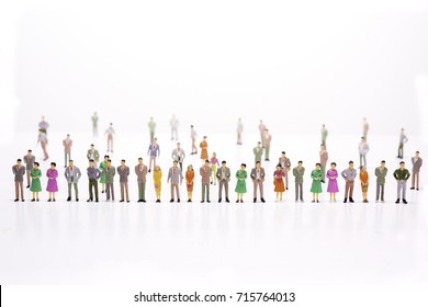 Group Of Miniature People Over White Background Standing In Line.