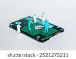 Group of miniature surgeon figurines collaborating on a hard drive, representing data recovery and technology intervention.