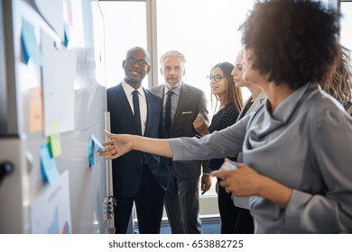 Group of mixed business people having a meeting using a white board in bright office space
