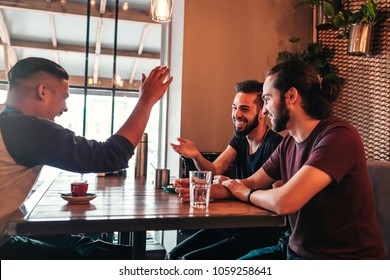 Group Of Mixed Race Young Men Talking In Lounge Bar. Multiracial Friends Having Fun In Cafe