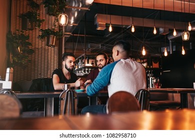 Group Of Mixed Race Young Men Talking In Lounge Bar. Multiracial Friends Hanging Out And Having Fun In Cafe