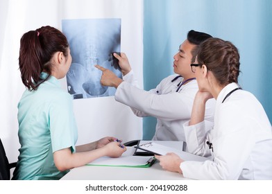 Group of mixed-race doctors analyzing x-ray, horizontal - Powered by Shutterstock