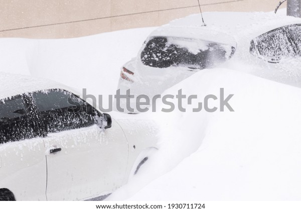 A group of modern cars covered in the snow parked\
outdoors in winter