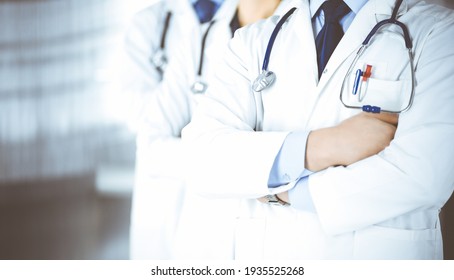 Group of modern doctors standing as a team with crossed arms and stethoscopes in hospital office. Physicians ready to examine and help patients. Medical help, insurance in health care, best desease