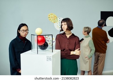 Group Of Modern Senior And Young People Visiting Exhibition In Art Gallery Looking At Various Contemporary Art Objects And Paintings