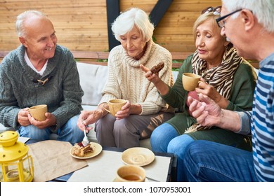 Group Of Modern Seniors Enjoying Time Together Drinking Tea In Outdoor Cafe And Sharing Life Stories In Retirement
