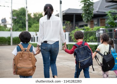 Group Of Mother And Kids Holding Hands Going To School With Schoolbag. Mom Bring Children Walk To School By Bus Together With Satchel. Back To School And Education Preschool. Parents Son Sister Family