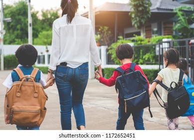 Group Of Mother And Kids Holding Hands Going To School With Schoolbag. Mom Bring Children Walk To School By Bus Together With Satchel. Back To School And Education Preschool. Parents Son Sister Family