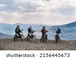 group motor travel offroad, motorcyclists standing on mountain top and taking pictures with phone, enjoying view 