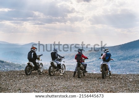group motor travel offroad, motorcyclists standing on mountain top and taking pictures with phone, enjoying view 