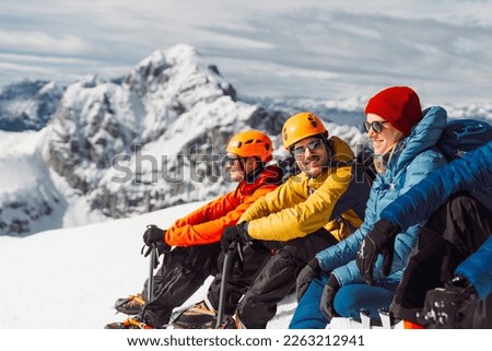 Group of mountaineers sitting in the sun on top of the snowy mountain