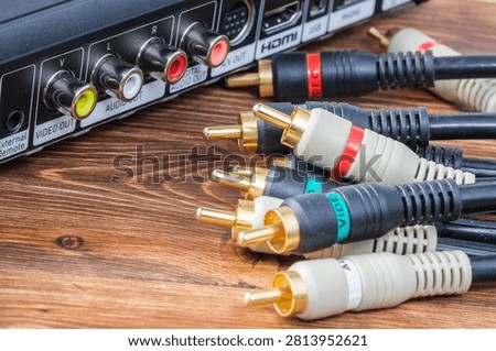 Group of multi colored analog RCA audio and video cable connectors near a multimedia device