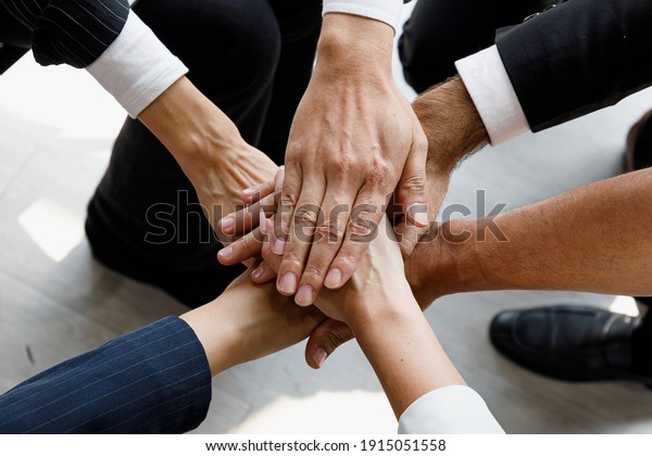 Group of multi colors hands\
stack together and smiling in the symbol of unity and strong\
teamwork.