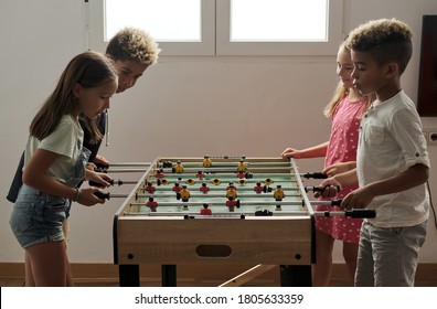 Group Of Multi Cultural Cute Children Stand Indoor Spend Playtime With Friends Playing Foosball Together. Tabletop Version Of Soccer Lovers. Having Fun And Recreation Of Alpha Generation Kids Concept