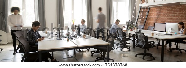 Group of multi ethnic corporate employees working\
in co-working open space walking in motion, sit at shared desks.\
Busy workday, office rush concept. Horizontal photo banner for\
website header design