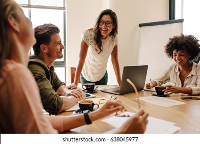Group of multi ethnic executives discussing during a meeting. Business man and woman sitting around table at office and smiling.